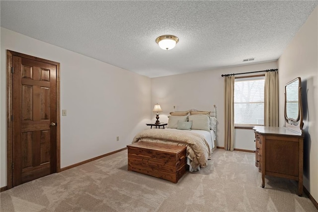 bedroom with light colored carpet and a textured ceiling