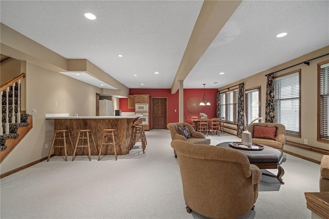 living room with light colored carpet, bar area, and a textured ceiling