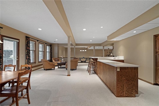 kitchen featuring light colored carpet, a textured ceiling, and kitchen peninsula