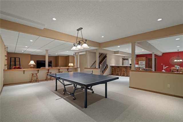 rec room with light colored carpet and a textured ceiling