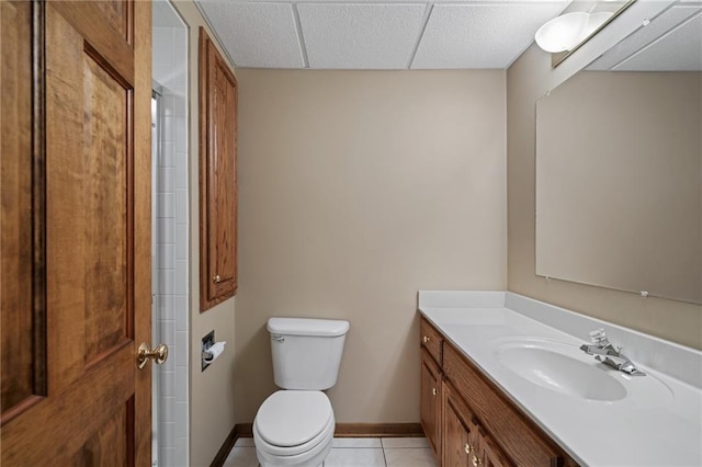 bathroom featuring a drop ceiling, vanity, tile patterned floors, and toilet