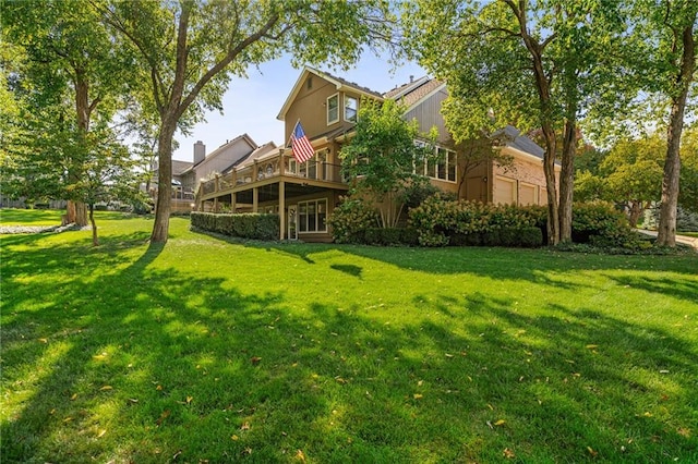 rear view of property featuring a wooden deck and a lawn