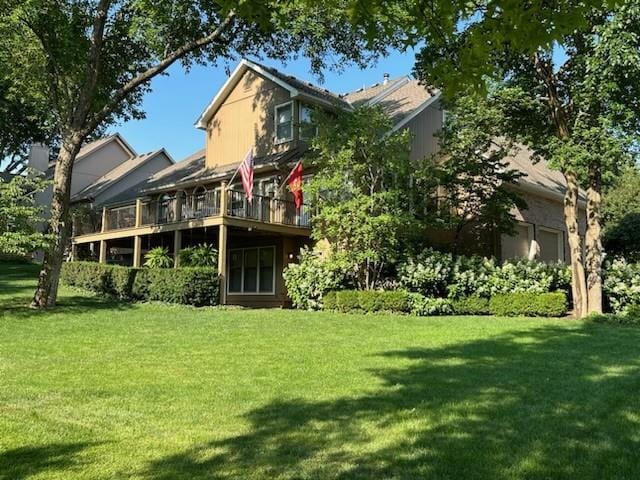 rear view of house featuring a wooden deck and a lawn