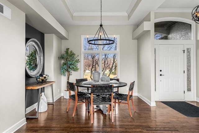 dining space featuring an inviting chandelier, dark wood-type flooring, ornamental molding, and a raised ceiling