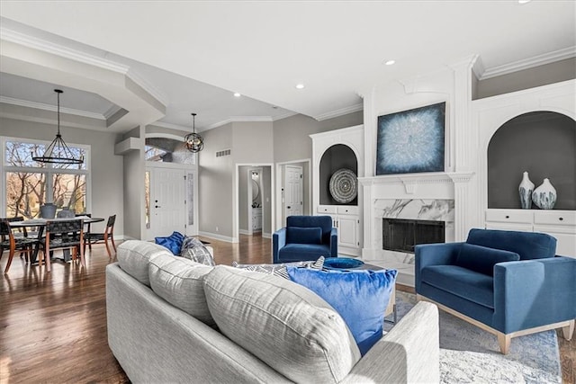 living room with crown molding, a fireplace, dark hardwood / wood-style flooring, and a chandelier