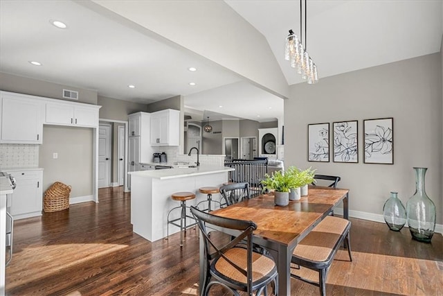 dining area featuring sink, vaulted ceiling, and dark hardwood / wood-style floors