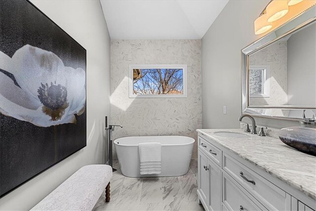 bathroom featuring lofted ceiling, vanity, and a tub