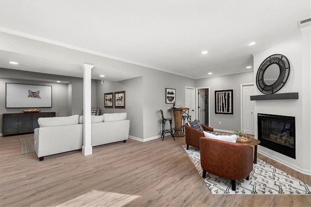 living room featuring ornamental molding, decorative columns, and light wood-type flooring