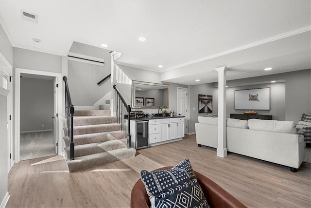 living room with wine cooler, ornamental molding, wet bar, and light hardwood / wood-style flooring