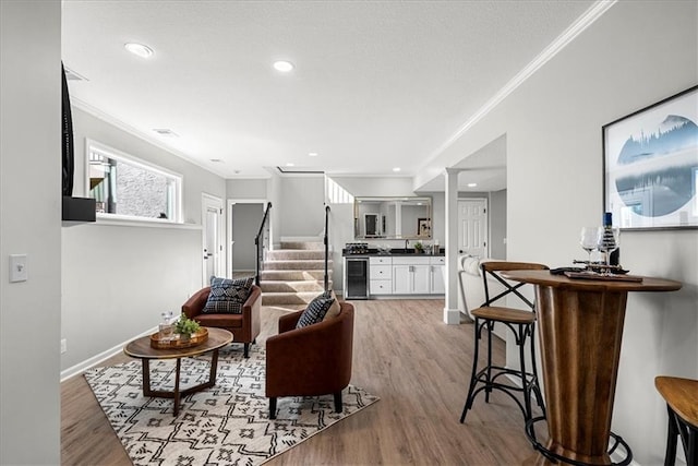 living room featuring crown molding, beverage cooler, and light hardwood / wood-style flooring