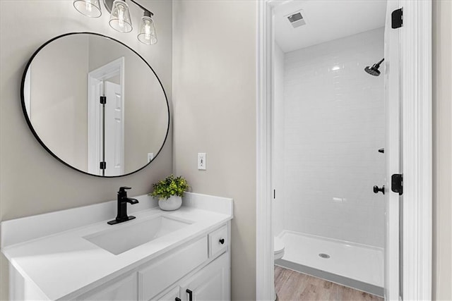 bathroom featuring tiled shower, vanity, toilet, and hardwood / wood-style floors