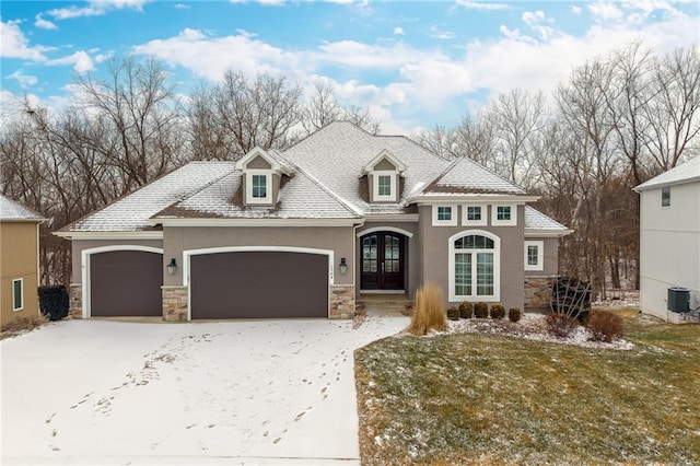 view of front facade featuring central air condition unit, a garage, french doors, and a lawn