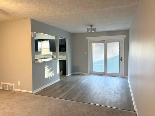 interior space with dark carpet, sink, and a textured ceiling