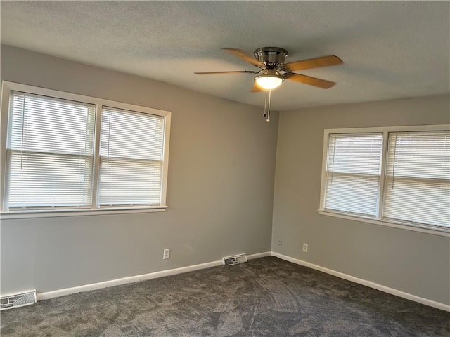 spare room with ceiling fan and dark carpet