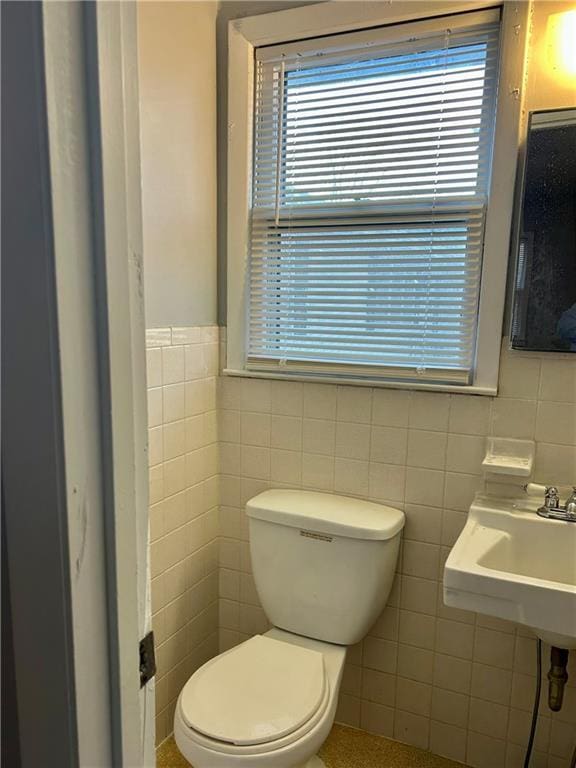 bathroom featuring toilet and tile walls