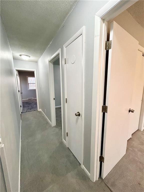 corridor with a textured ceiling and carpet flooring