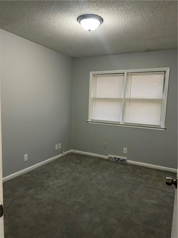 carpeted empty room with a textured ceiling