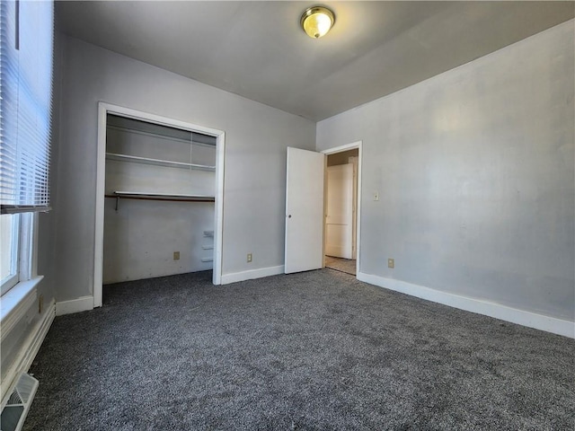 unfurnished bedroom with dark carpet and a closet