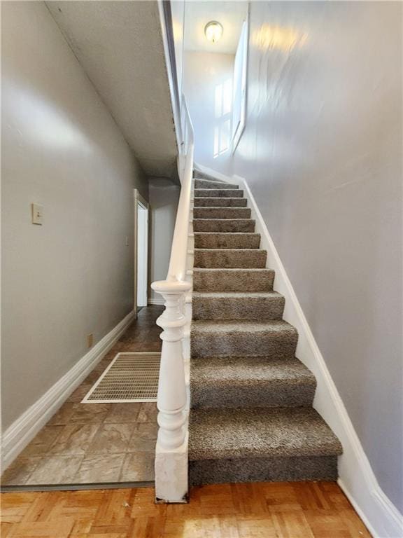 staircase featuring parquet flooring