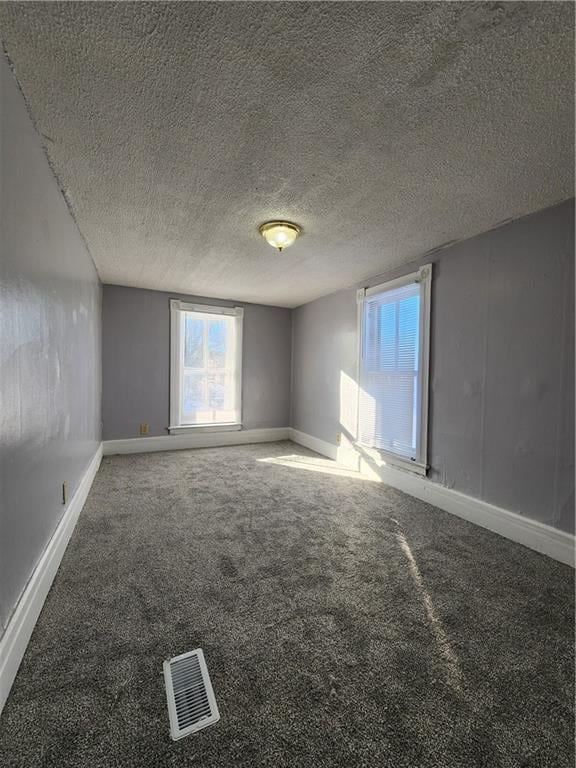 carpeted empty room featuring a textured ceiling