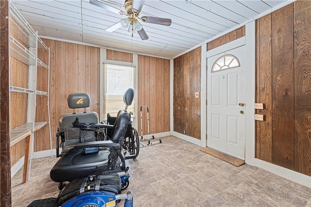 workout area featuring ceiling fan, wood ceiling, and wood walls