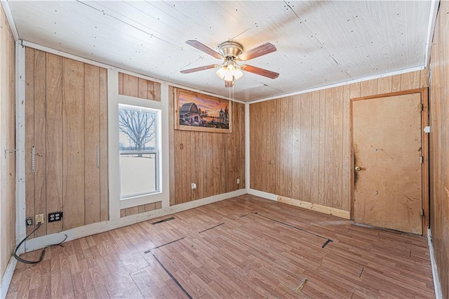 unfurnished room with wood walls, ceiling fan, ornamental molding, and hardwood / wood-style flooring