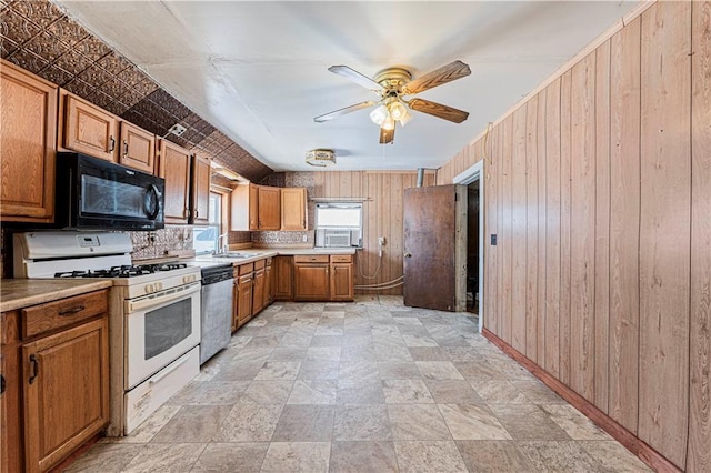 kitchen with sink, white gas stove, dishwasher, and wooden walls