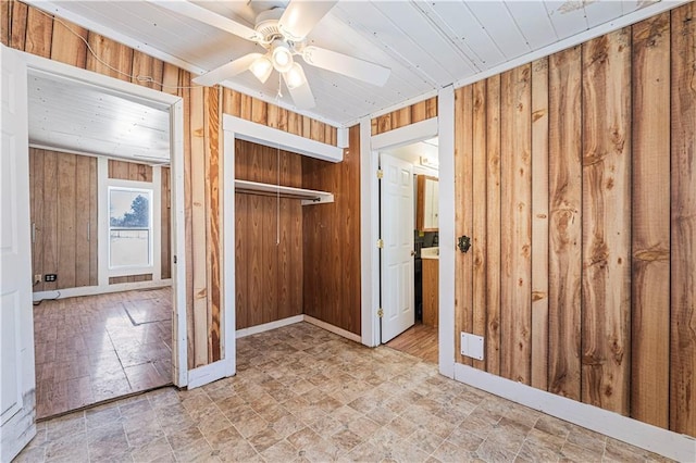 interior space with ceiling fan, a closet, and wooden walls