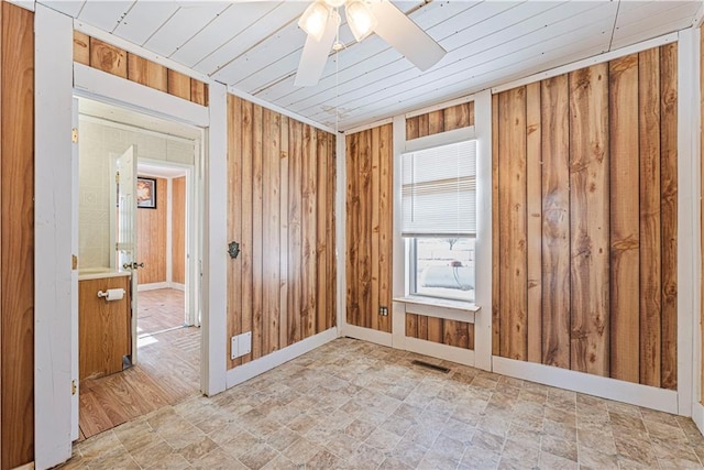 empty room with ceiling fan and wood walls