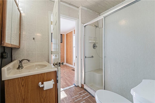 bathroom featuring hardwood / wood-style floors, vanity, tile walls, toilet, and walk in shower