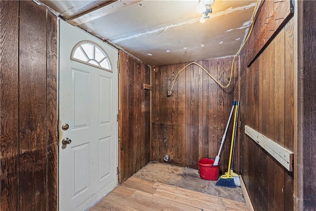 foyer with light wood-type flooring and wooden walls