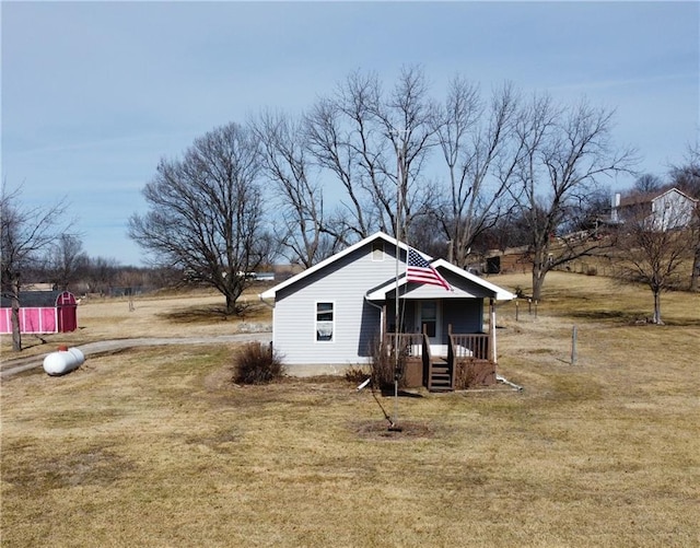 view of outbuilding featuring a rural view, covered porch, and a lawn