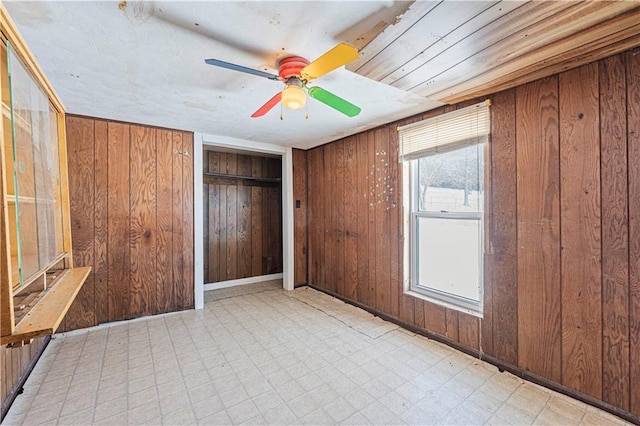 unfurnished bedroom featuring ceiling fan and wood walls