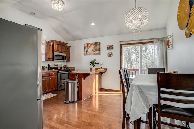 kitchen featuring decorative light fixtures, lofted ceiling, a kitchen bar, a chandelier, and stainless steel appliances