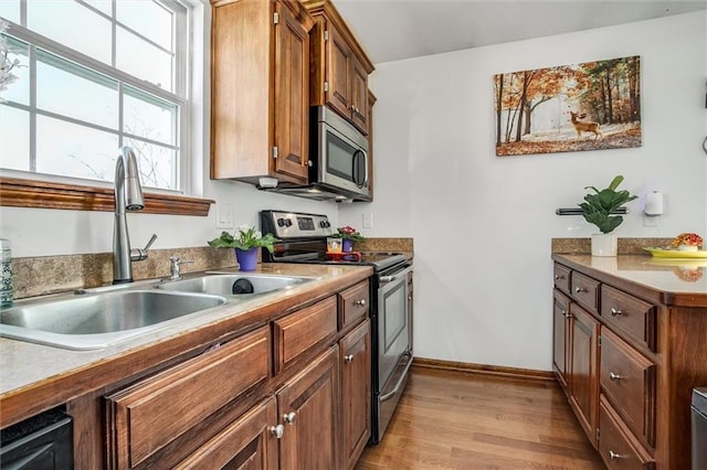 kitchen with sink, stainless steel appliances, and light wood-type flooring