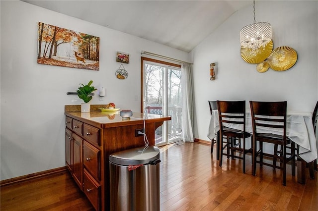 dining area featuring lofted ceiling, dark hardwood / wood-style floors, and a chandelier