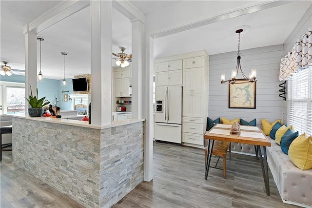 kitchen featuring ceiling fan with notable chandelier, white fridge with ice dispenser, breakfast area, decorative light fixtures, and light wood-type flooring