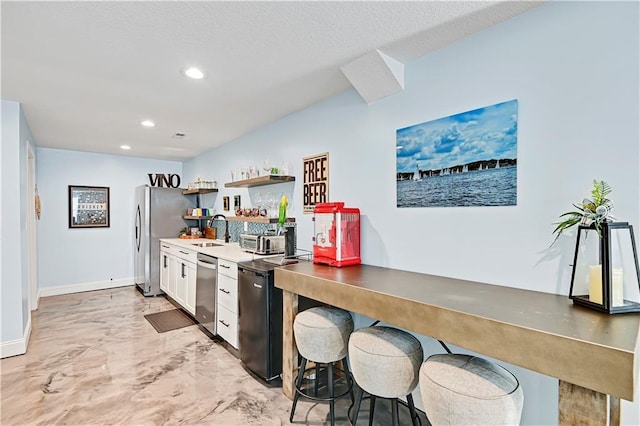 kitchen featuring white cabinets, a kitchen breakfast bar, appliances with stainless steel finishes, and sink