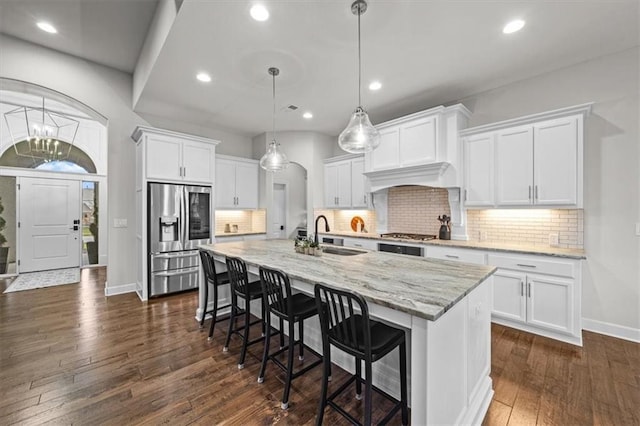 kitchen with stainless steel appliances, light stone countertops, pendant lighting, and white cabinets