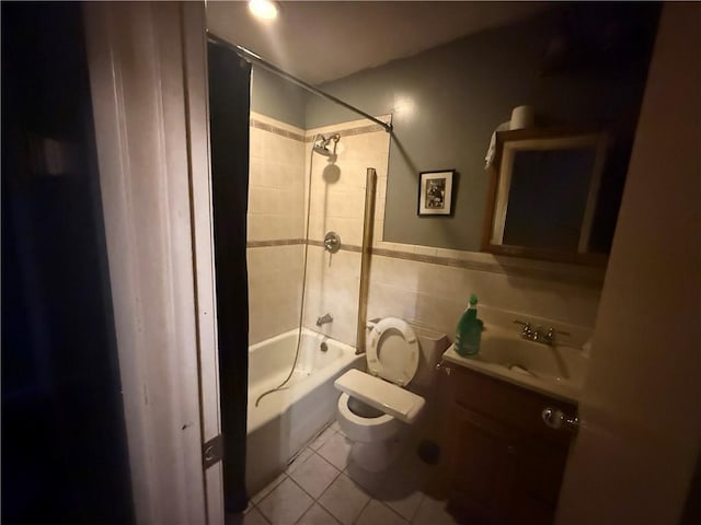 full bathroom with tile walls, tile patterned flooring, vanity, tiled shower / bath combo, and toilet