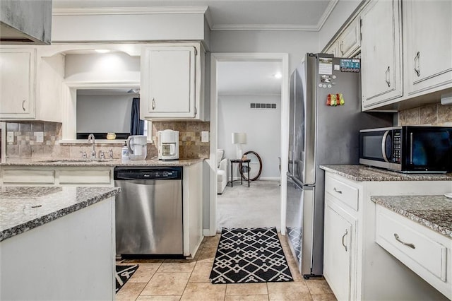 kitchen featuring visible vents, a sink, ornamental molding, stainless steel appliances, and tasteful backsplash