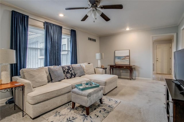 living room with a ceiling fan, baseboards, light colored carpet, and crown molding