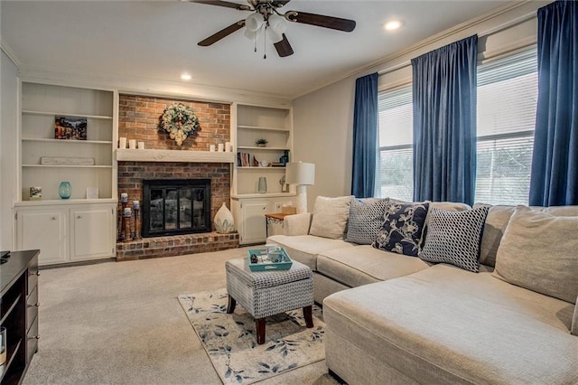 carpeted living area with built in features, a fireplace, recessed lighting, ceiling fan, and ornamental molding