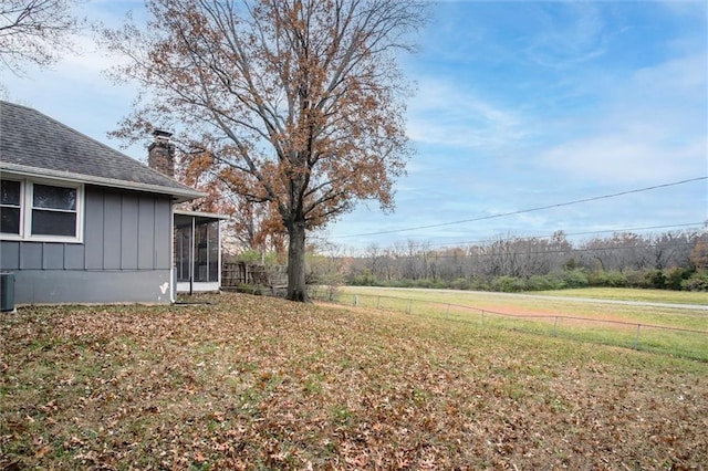 view of yard featuring central air condition unit, fence, and a sunroom