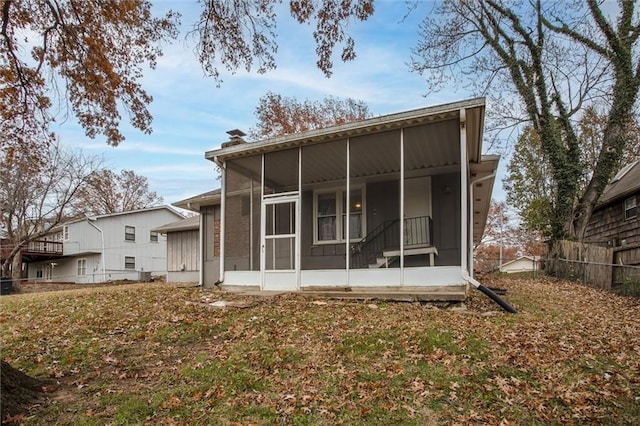 rear view of house featuring fence, a chimney, and a sunroom