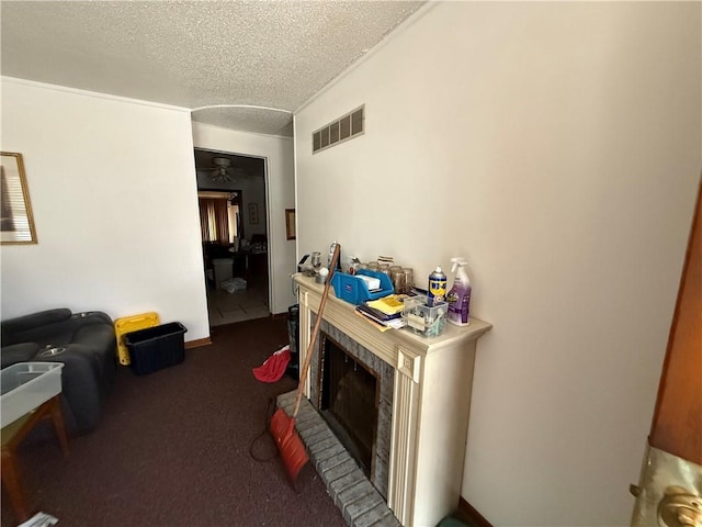 interior space with a brick fireplace, dark carpet, and a textured ceiling