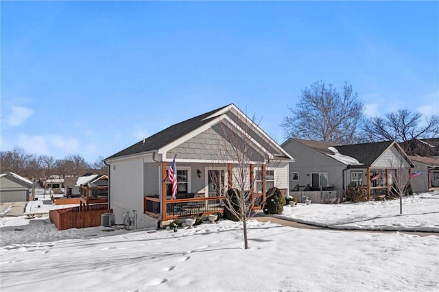 snow covered rear of property featuring covered porch and central AC