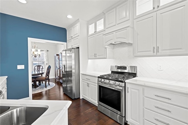 kitchen featuring white cabinetry, stainless steel appliances, tasteful backsplash, dark hardwood / wood-style floors, and light stone counters