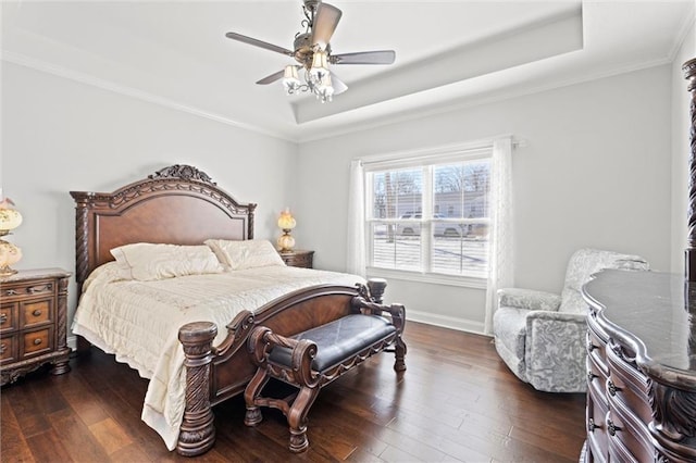 bedroom featuring dark wood-type flooring, ceiling fan, crown molding, and a tray ceiling