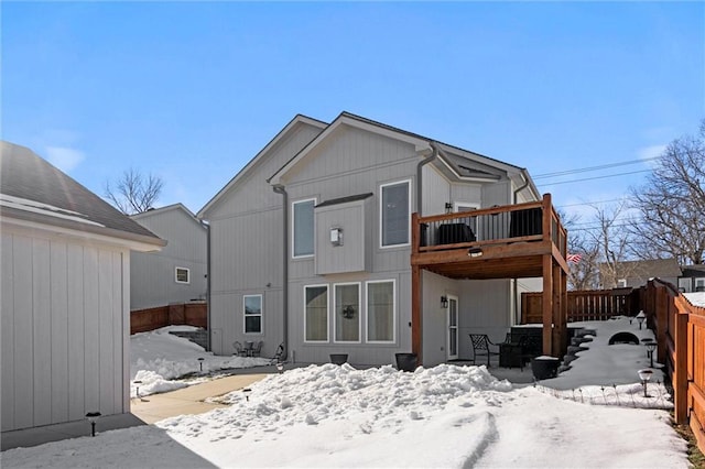 snow covered rear of property with a wooden deck